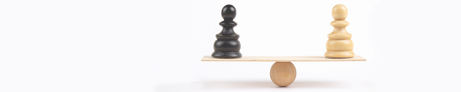 Black and white chess pawns are balanced on a wooden seesaw.