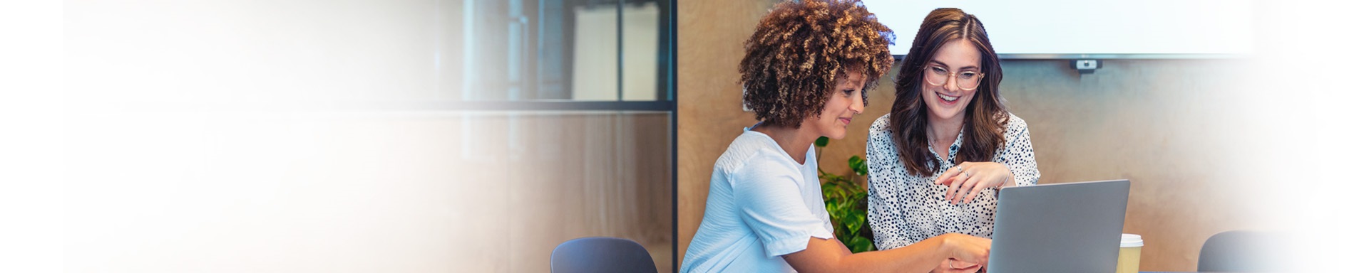 Deux femmes sont assises au bureau et regardent l'écran d'un ordinateur portable.